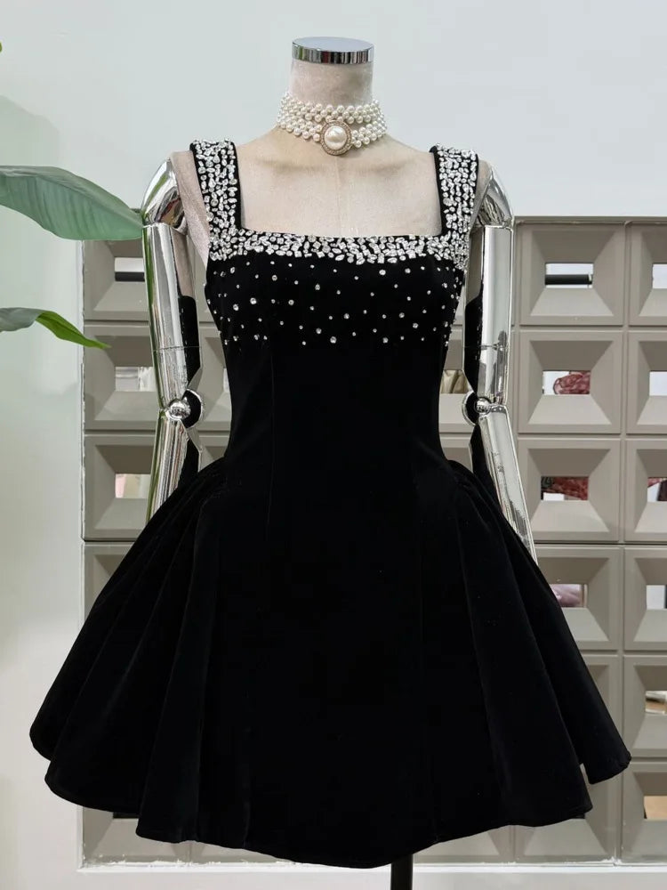 Black velvet-look mini dress on a mannequin with a square neckline, rhinestone-trim straps, and a dramatic fit-and-flare skirt.