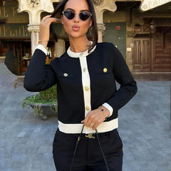 Woman wearing a black and white contrast knitted cardigan styled for casual outdoor looks with sunglasses in an outdoor setting