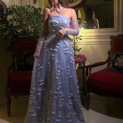 Woman in a blue evening gown standing in an elegant room with red chairs and floral decorations.