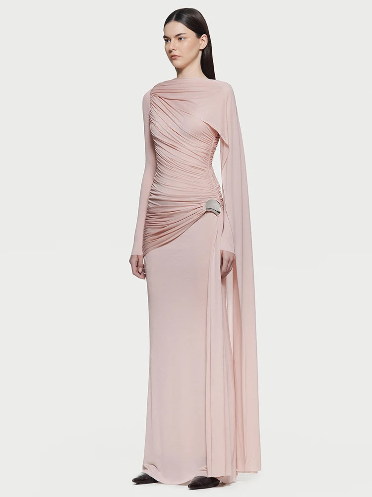 Model wearing a blush draped asymmetrical evening gown with long sleeves