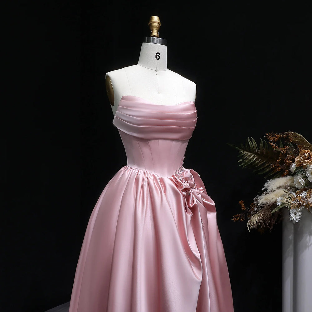 Backless strapless satin prom gown shown from a side angle
