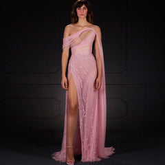 A woman wearing an elegant blush pink off-shoulder ball gown with a high leg slit.

