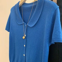 Blue cardigan with a necklace on a beige background