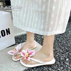 Breathable gingham pattern shoes perfect for summer outings.White sandals with pink floral designs worn by a person on a stone surface.