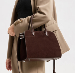Close view of the brown suede handbag highlighting rounded top handles, clean edge finishing, and the softly structured silhouette.
