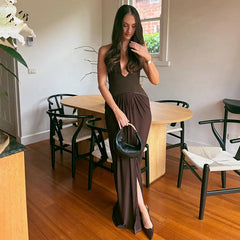 Lower-half detail showing the pleated skirt falling to the floor, capturing the drape and movement against a neutral studio-style setting.