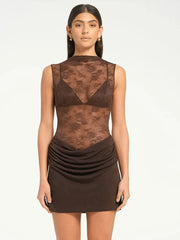 Woman wearing a brown lace bodysuit with a plain background