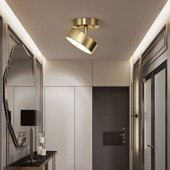 Modern round LED ceiling light with a copper finish and a warm glow, mounted on a recessed ceiling in a bath room pointing over a mirror.