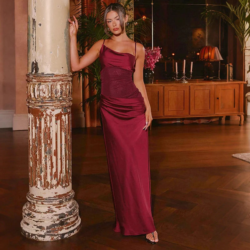 Woman posing in a burgundy satin maxi dress beside a vintage column, showing the square neckline and floor-length A-line sweep.