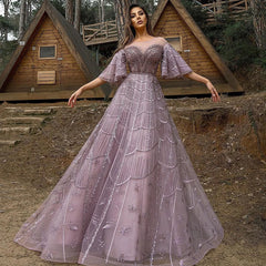A woman modeling a long burgundy A-line tulle gown with a beaded bodice.
