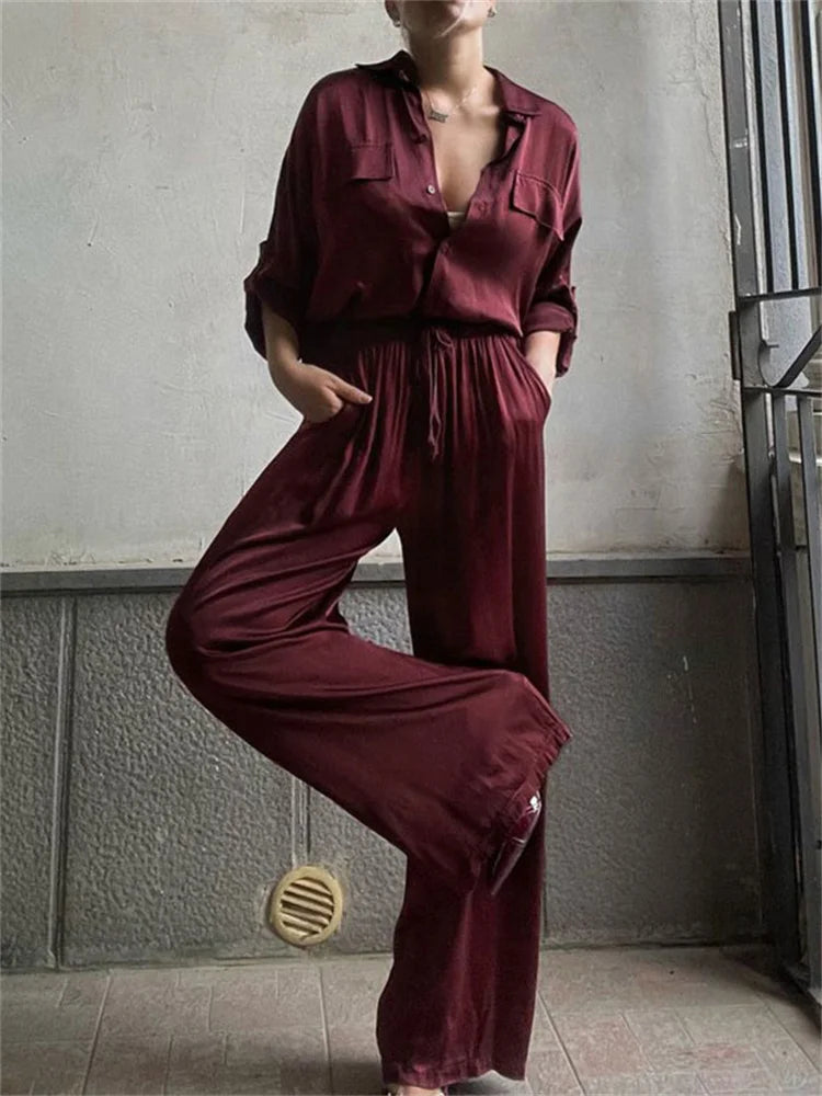 A person wearing a Two-piece satin outfit styled with heels in a minimal interior.