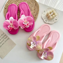 Pink flip-flops with floral decorations on a white surface