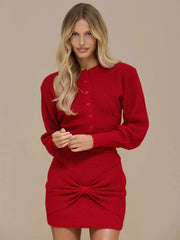 Studio front view of a red knit two-piece set with a button-front long-sleeve top and a mini skirt with bow twist detail.