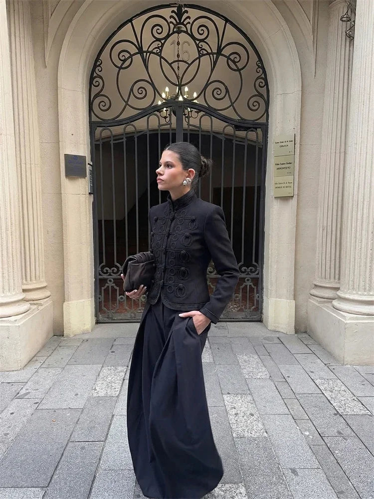 Street-style moment with a black textured blazer and mandarin collar, styled with a clutch bag for an elevated work-to-evening outfit.
