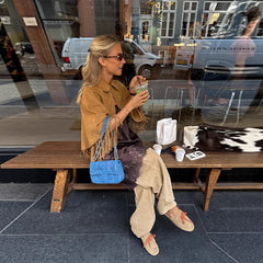 Street-style look featuring a camel-toned fringe cape coat paired with neutral separates, highlighting the coat’s drape and texture.