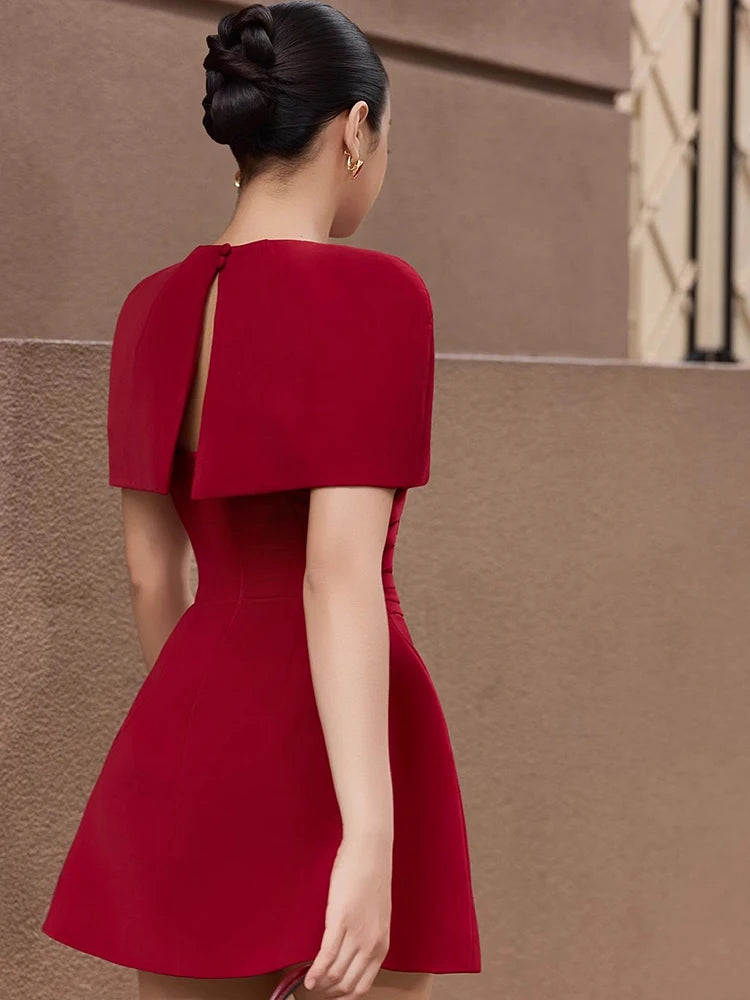 Detail of the cape overlay across the shoulders, showing sculpted coverage and a refined, modern silhouette designed for cocktail occasions.
