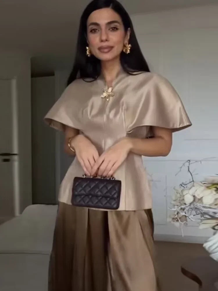 Front view of a cape-sleeve top with a defined waist silhouette