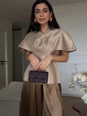 Front view of a cape-sleeve top with a defined waist silhouette