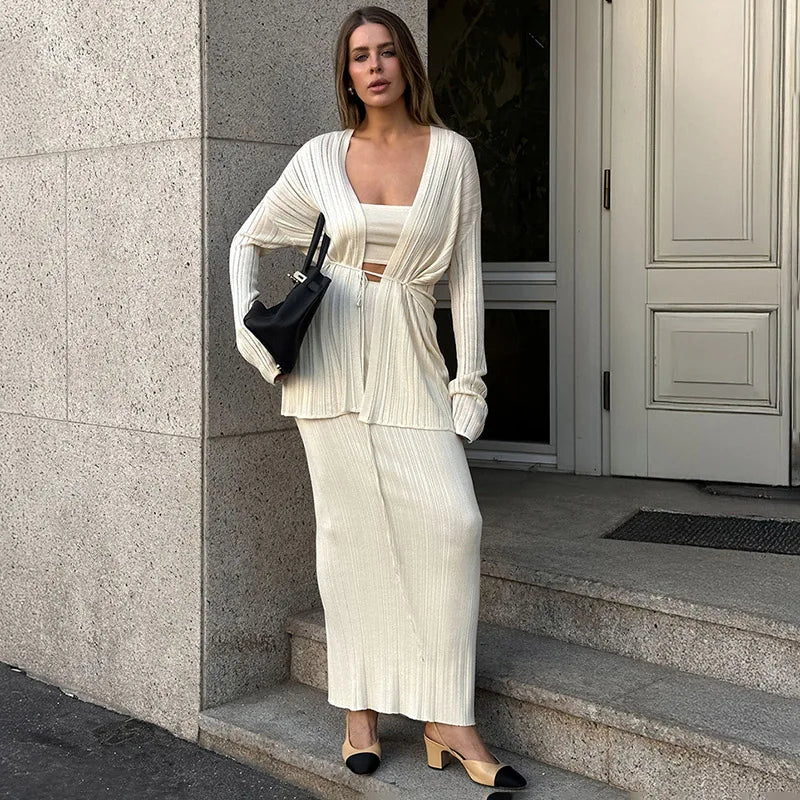 Woman in a cardigan lace-up crop top long skirt set in gray for autumn city fashion standing outside a building