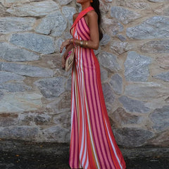 Woman in a  Mid-calf striped dress with a halter neckline standing against a stone wall.