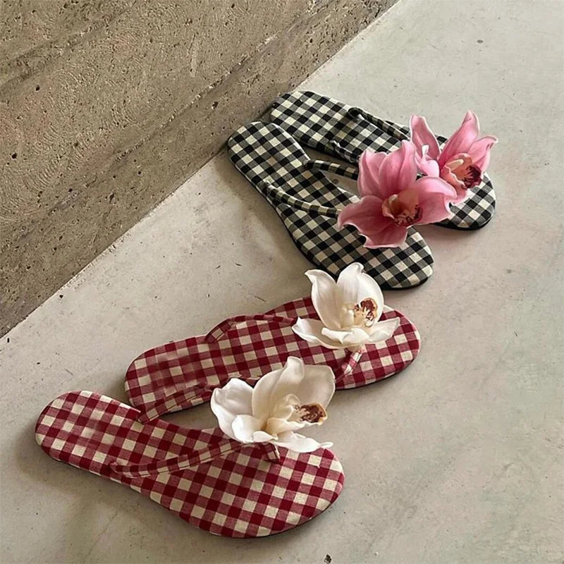Pair of checkered flip-flops with flowers on a concrete surface