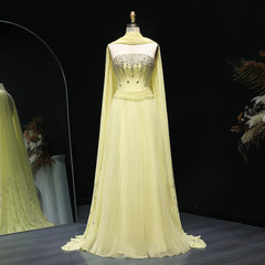 Champagne colored  evening gown with a cape on a mannequin against a dark background