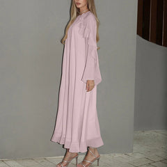 Close-up of tiered sleeve detail and lightweight fabric worn by a woman against a grey wall.