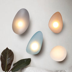 An image displaying multiple Color Glass LED Wall Lamps with a soft, warm light glowing from within, mounted on a wall. Each lamp has an egg-shaped design with a translucent glass cover.