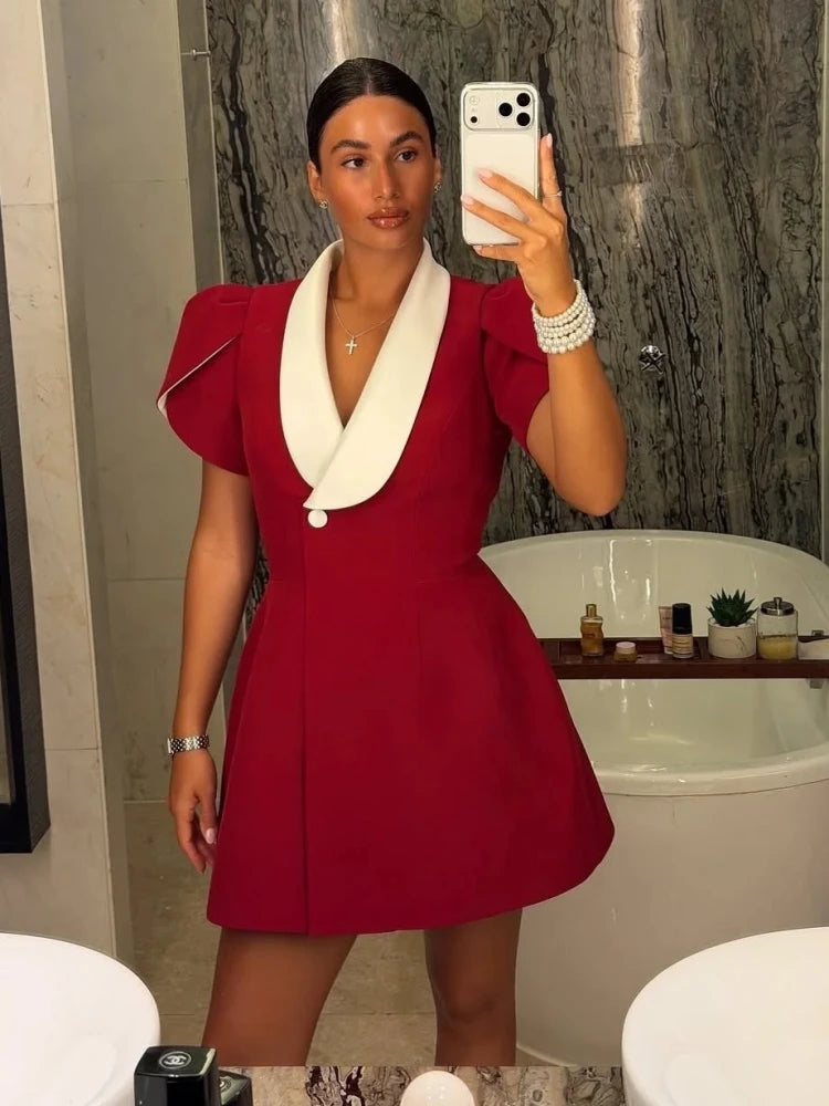 Close-up of the deep V neckline and white collar detailing on a black mini dress, paired with delicate jewelry for a refined look.