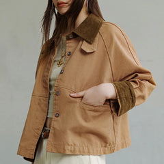 Person wearing a brown jacket with a green collar against a gray background