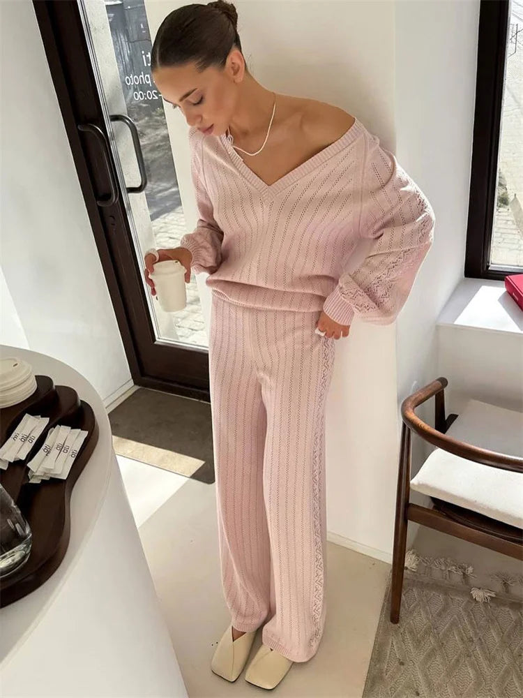 Woman  in cozy two-piece knit outfit in soft pink styled  standing in a modern interior setting.
