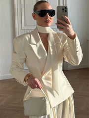 Woman wearing cream lace-up blazer with wrap tie and sunglasses