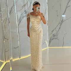 Woman in a gold evening gown taking a mirror selfie against a marble wall.
