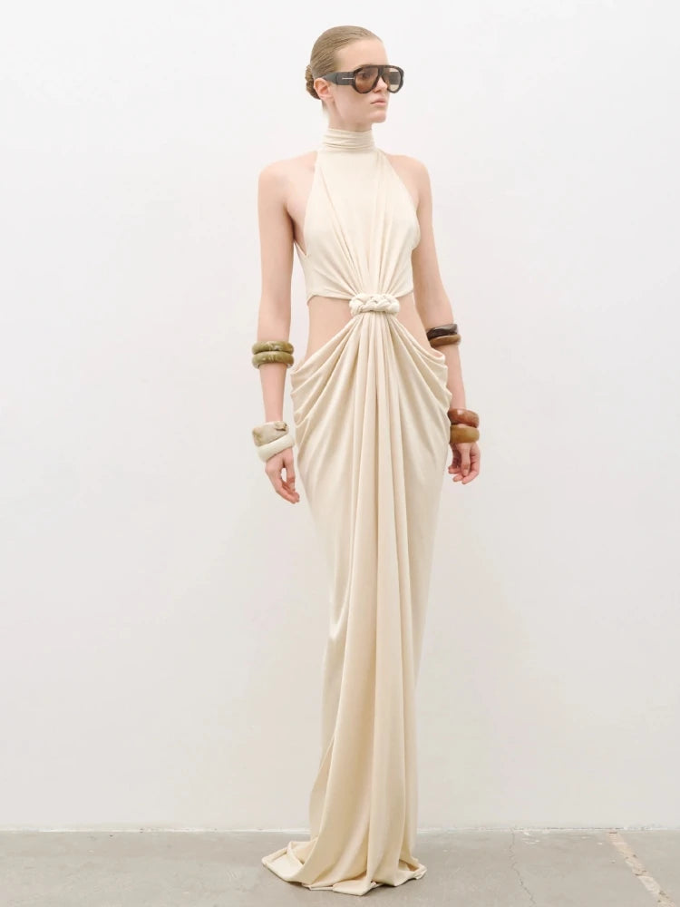 Full-length studio view of a cream sleeveless maxi dress with high round neckline, twist-knot front and soft draped skirt.