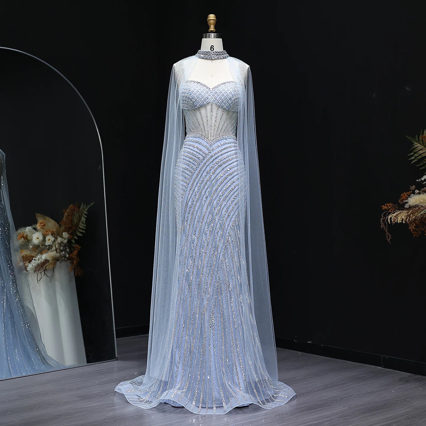 Elegant crystal mermaid evening gown with sheer cape in lilac for luxury events on a mannequin against a dark background