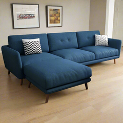A blue fabric sofa with a chaise on the left side, featuring a modern design with button tufting and wooden legs, with two accent pillows on the sofa.