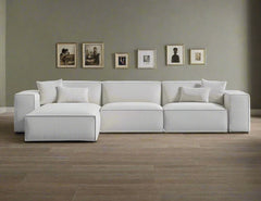 A beige modular combination porter sectional sofa with multiple cushions, displayed in a bright and spacious room, grey wall and multiple pictures. 