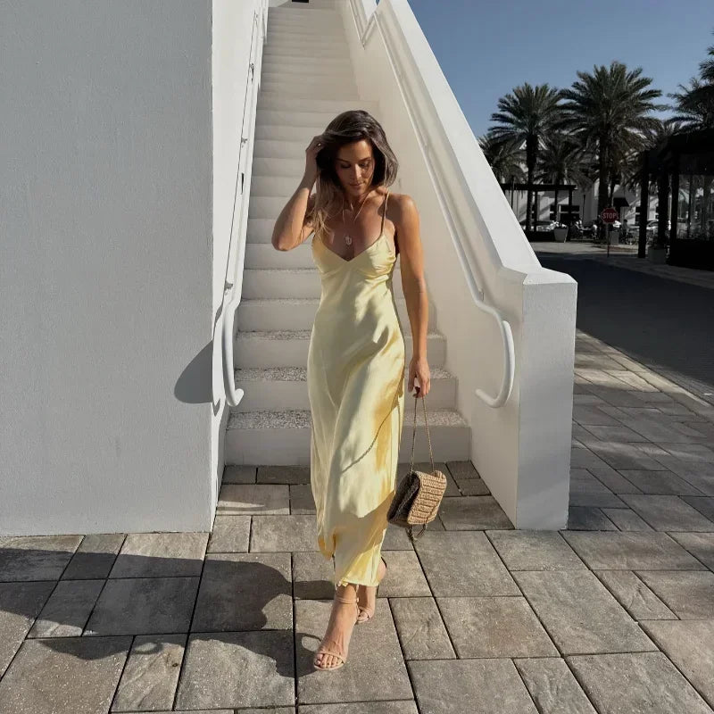 Woman in a yellow dress walking on a stone path with palm trees in the background