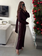 Model wearing a deep burgundy long sleeve satin dress with lace-up detail