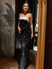 Full-length view of black gown featuring bow cape detail and embellished accents