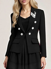 Model wearing a black double-breasted blazer with decorative buttons, styled over a dress in a clean studio setting.