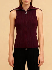 Model wearing a sleeveless knit top with double zipper detail, standing against a soft studio backdrop