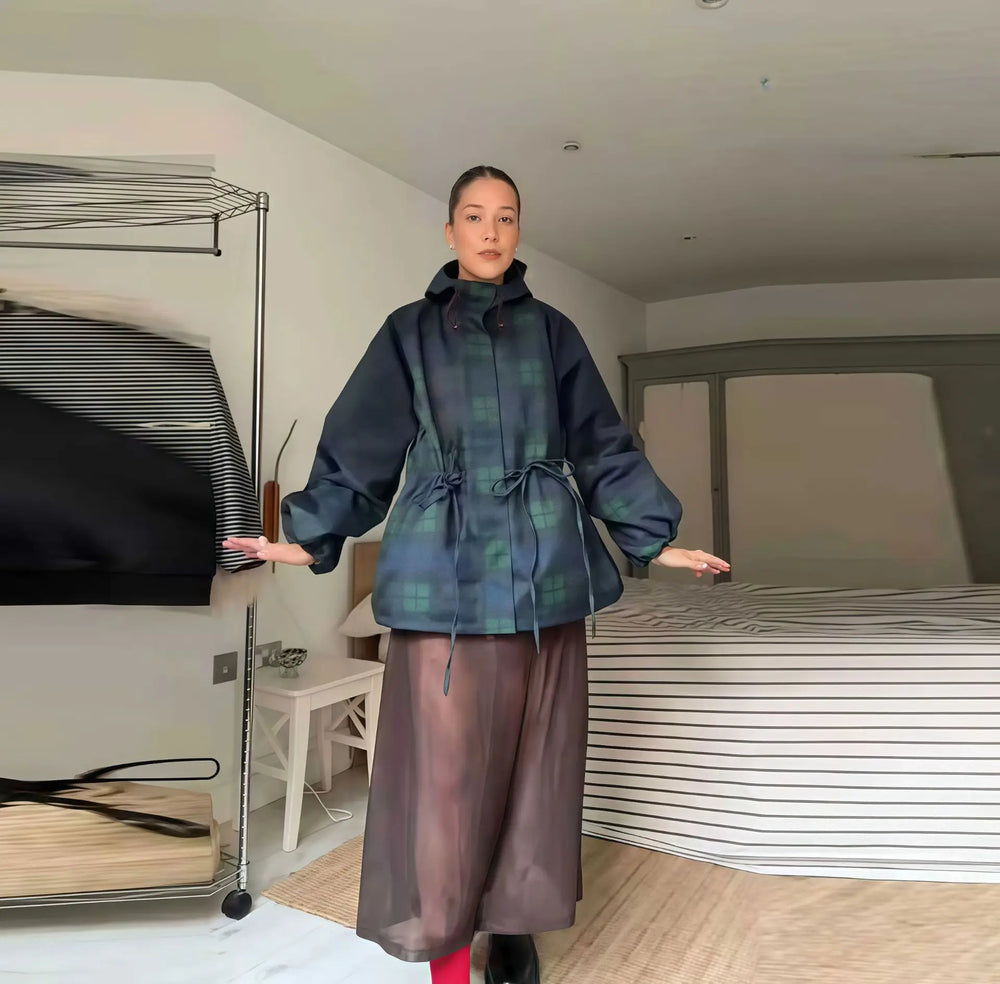 Person wearing a plaid jacket and sheer pants in an indoor setting