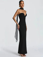 Woman wearing a black strapless gown with a sheer scarf on a white background
