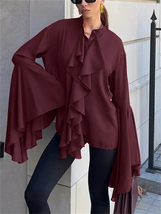 A woman wearing an Elegant burgundy ruffle blouse styled with black pants outdoors