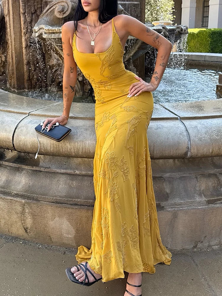 Woman in a yellow evening gown standing by a fountain