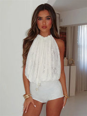 A woman wearing of lace hollow-out halter neckline on a white playsuit in an indoor setting