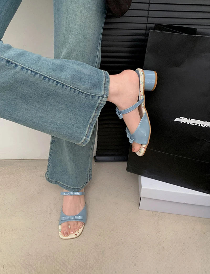 Open toe blue block heel slides on black surface