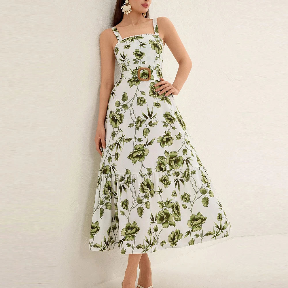 Woman wearing an elegant belted summer dress styled with a straw bag and sandals with green flowers on a white background