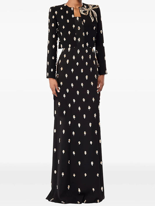 Model wearing a maxi dress with an all-over embellished motif and a cropped blazer, styled as a coordinated formal set on a studio background.